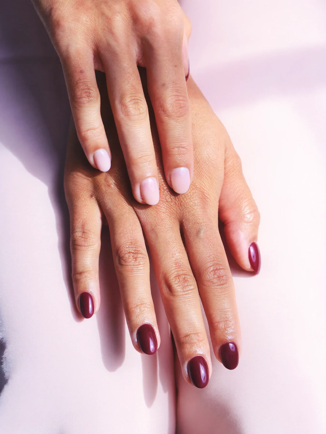 Glossy dark cherry manicure on softly posed hands